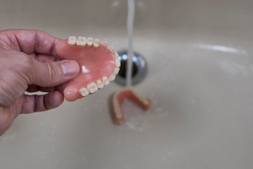 denture cleaning with water / denture cleaning with water in the sink with running water