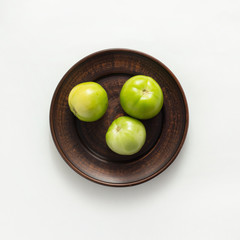 green tomatoes on plate white background top view