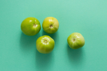 green tomatoes on green background top view
