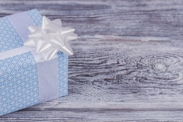 Beautiful gift box and copy space. Present box packed in blue paper with white bow on wooden...