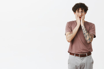 Gosh that is shocking. Portrait of stunned good-looking young urban male in shook with tattooed arm...