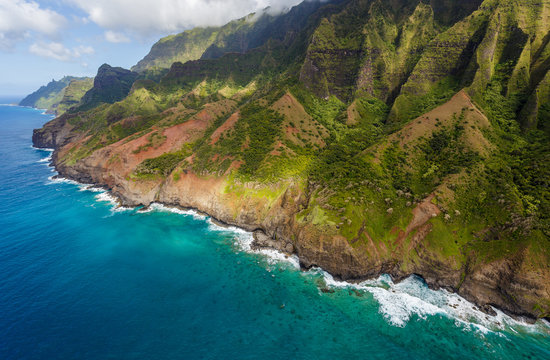 View of the monumental Na Pali Coast at Kaa Alahina Ridge and Manono Ridge, Kalalau trail visible if zoomed in. Aerial shot from a helicopter, Kauai, Hawaii.