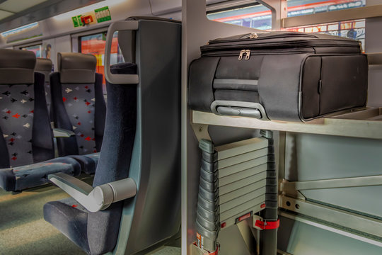 Black suitcase on the shelf in the train car.