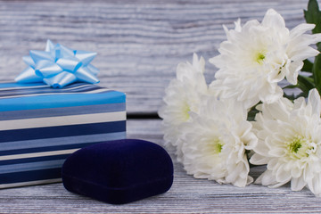 Fototapeta na wymiar Gifts and flowers on wooden background. Bouquet of white chrysanthemum and blue jewelry box. Holiday greeting card.
