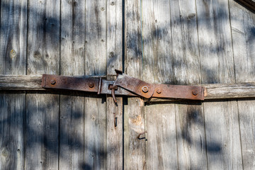 Rusty, old, handmade  gate lock  on pine wooden boards close up shot on a bright sunny day, 