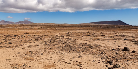 dry and rocky desert landscape with  mountains in the distance
