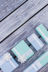 Holiday presents on wooden background. Wrapped in blue and turquoise paper gifts for Christmas, Birthday or other celebrations, top view.