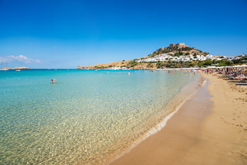 Fototapeta premium View of sandy beach in Bay of Lindos, Acropolis in background (Rhodes, Greece).