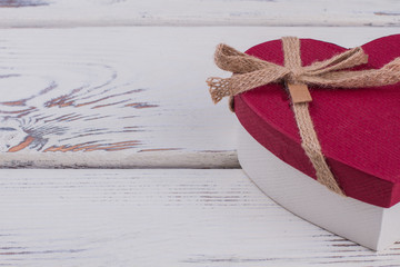 Valentines Day gift box with copy space. Red heart-shaped present box on wooden background.
