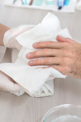 Męskie dłonie wycierane ręcznikiem przez dłonie kosmetyczki podczas zabiegu kosmetycznego...