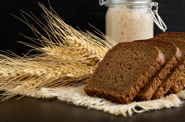 Sliced rye bread on black background with ears.