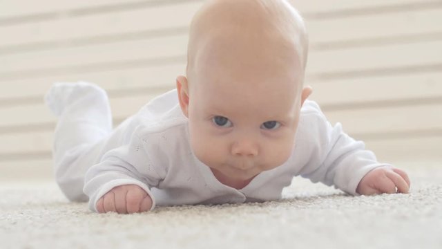 Happy Baby Lying on Carpet Background, Smiling Infant Kid girl in White Clothing
