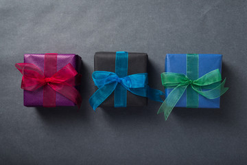 Wrapped presents with colorful ribbons over dark grey background, top view