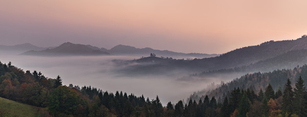 Panoramic foggy landscape at dawn over mountain and valley