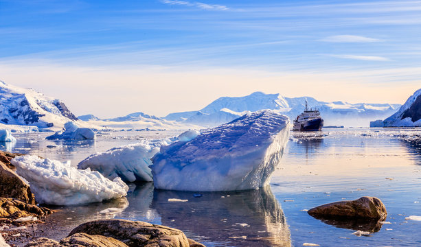 Touristic antarctic cruise ship among the icebergs with glacier in background, Neco bay, Antarctica