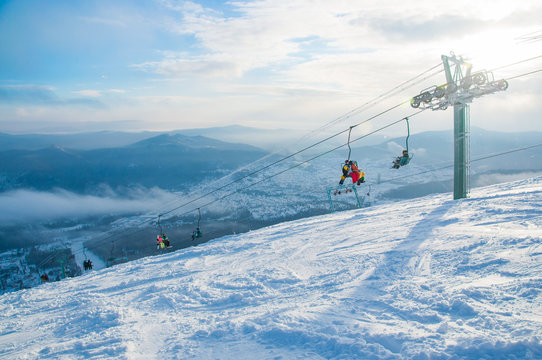 Ski lift with snowboarders and skiers. Blue sky and sun. Sheregesh ski resort. Sheregesh is one of the most famous ski resorts of Russia. Mountain Shoria. Winter holiday.