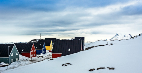 Colorful inuit houses along the street covered in snow, at the fjord in a suburb of arctic capital Nuuk, Greenland