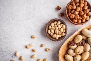 Hazelnuts, pistachio and pecans in wooden bowls on white background.