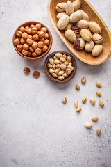 Hazelnuts, pistachio and pecans in wooden bowls on white background.