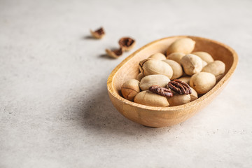 Pecan nuts in a wooden bowl on a white background.