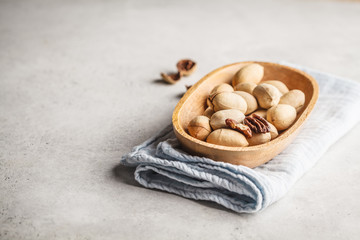 Pecan nuts in a wooden bowl on a white background.