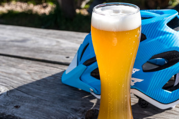 Weizenbier und blauer Fahrradhelm auf Holztisch