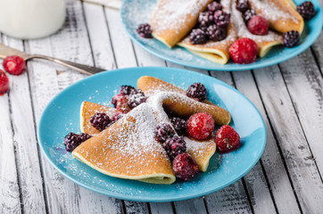 Homemade crepes with frozen berries, topped sugar