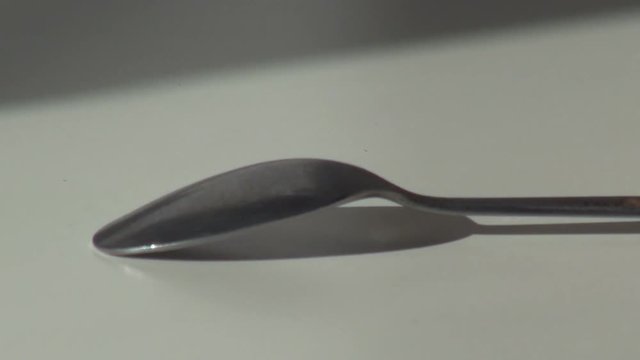 hand puts a teaspoon on the table