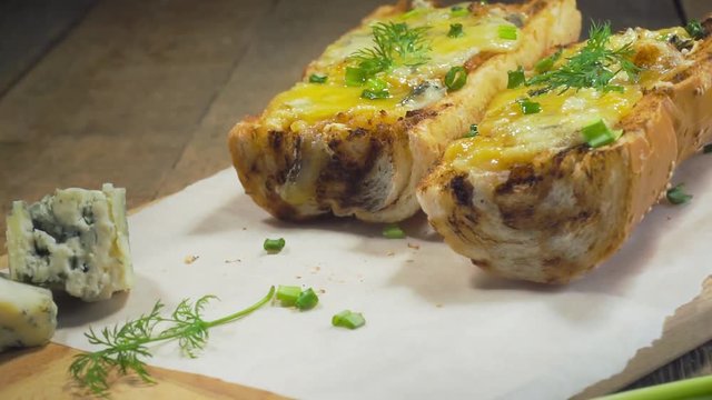 Baked open faced cheese sandwiches with mozzarella, gorgonzola and green onion on a rustic wooden table.
