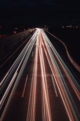 Fototapeta na wymiar White light trails from cars on a traffic motorway at night view. Abstract motion blur movement
