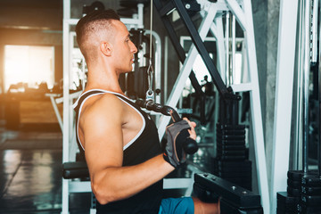 Fototapeta na wymiar Man flexing muscles on cable machine in gym