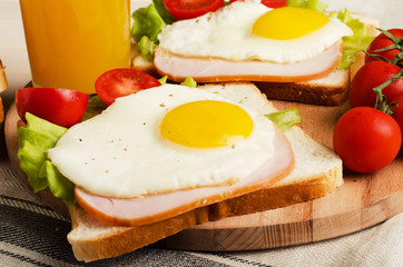 Fried egg with ham, salad and tomatoes sandwich
