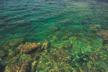 stones and rocks under water surface with waves of warm south tropic sea, foreshortening from above