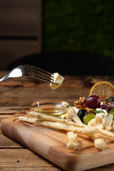 Piece of cheese on fork above the cheese platter