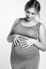 A beautiful pregnant woman with blond hair in a tight knitted dress. Black and white photo.