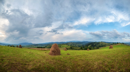haystack on top of mountain and amazing cloudy sky. rural summer (autumn) panoramic landscape