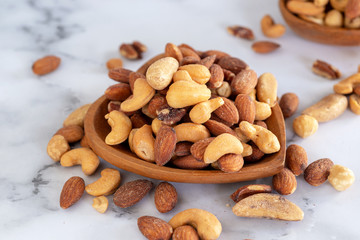 roasted mixed nuts in wooden bowl on barble table background.
