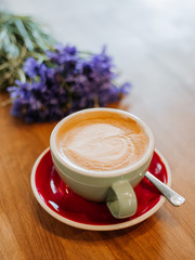 latte on wooden desk with flower cornflower in retro film filter effect