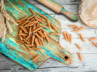 Wholemeal pasta on green rustic wooden chopping board