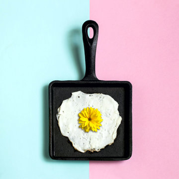 Cast-iron frying pan with fried eggs, flower of rudbeckia instead of yolk
