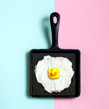 Cast-iron frying pan with fried eggs, toy duckling instead of yolk