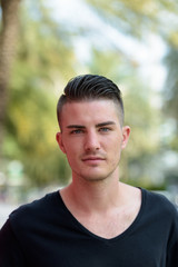 Portrait of young handsome man looking at camera outdoors