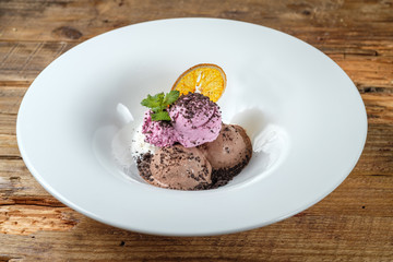 Three kind of ice cream balls with mint and a slice of orange