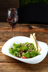 Glass of red wine and vegetarian salad with cheese and vegetables