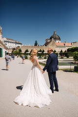 Fototapeta premium Beautiful young bride with her handsome groom walking in palace Belvedere