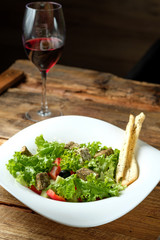 Glass of red wine and vegetarian salad with cheese and vegetables