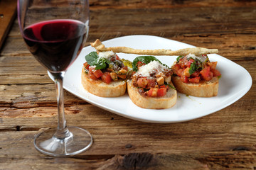 Glass of red wine and bruschetta with fresh tomatoes, parmesan and basil