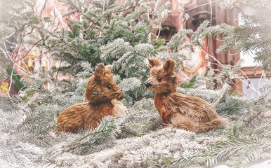Two handmade Christmas foxes on Christmas tree branches