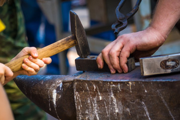 blacksmith performs the forging of hot glowing metal on the anvil