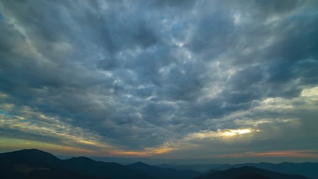 The beautiful cloud stream with a sunset above mountains. time lapse